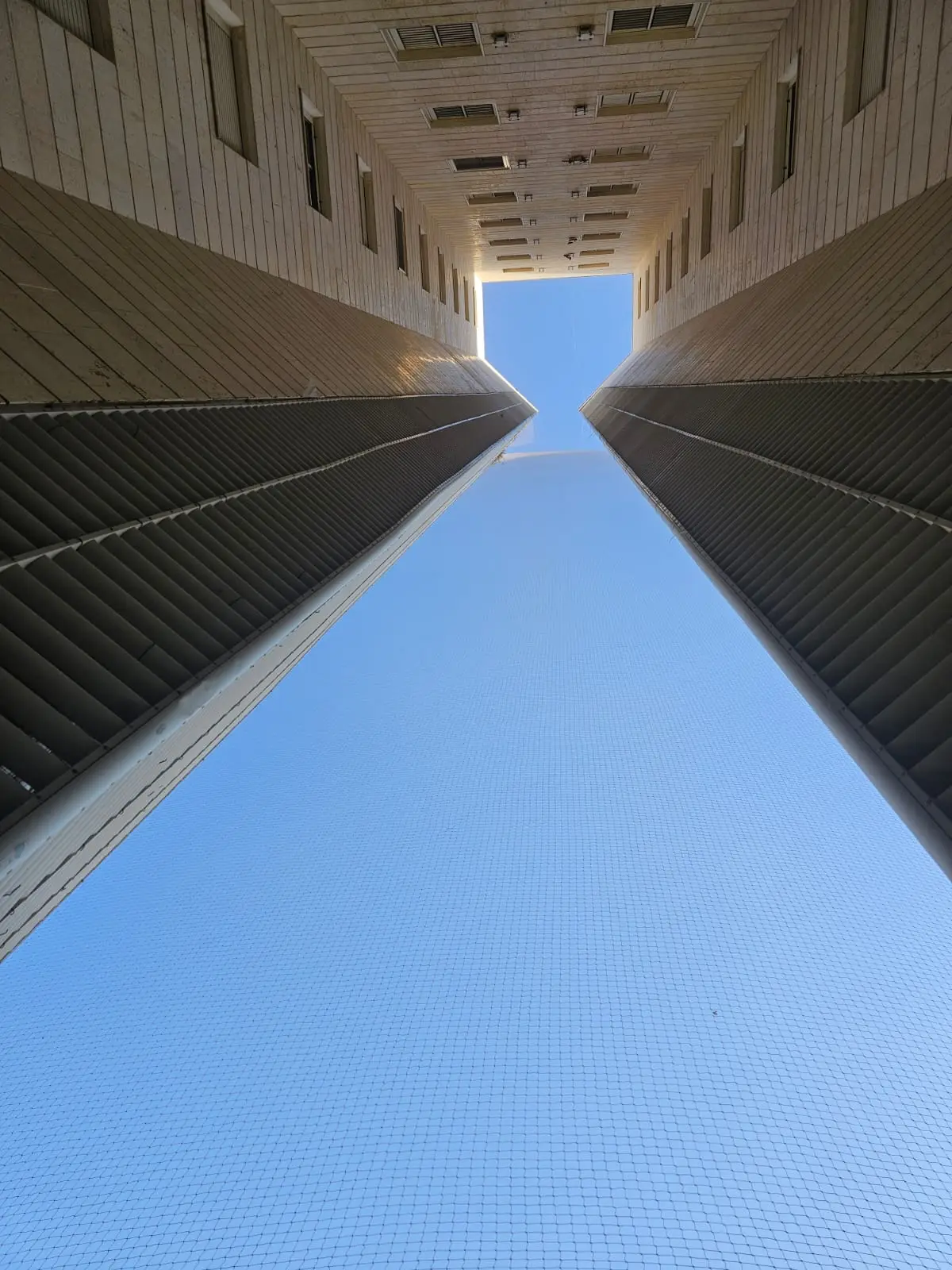 התקנת רשת יונים שקופה והרמטית על מעטפת בניין גבוה בשיטת סנפלינג - סקיינט פתרונות גובה.